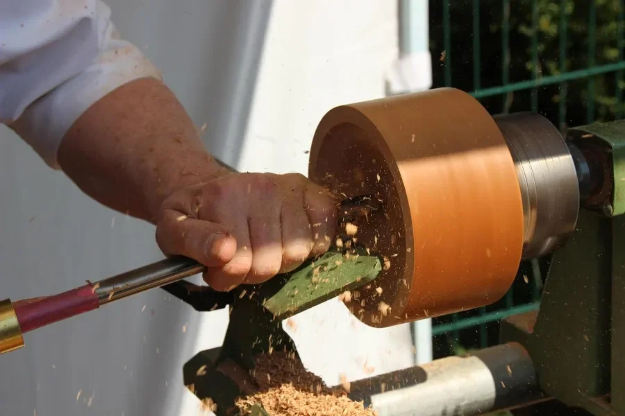 Woodturner shaping a small wooden piece on a lathe