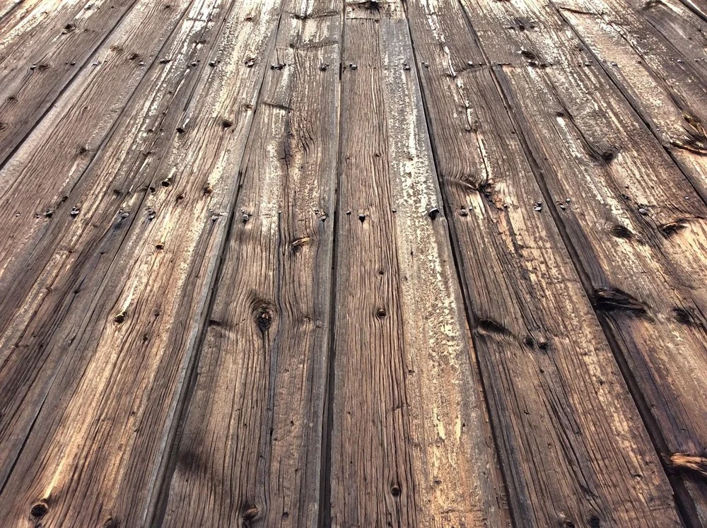 Weathered barnwood planks with old nail holes and worn paint