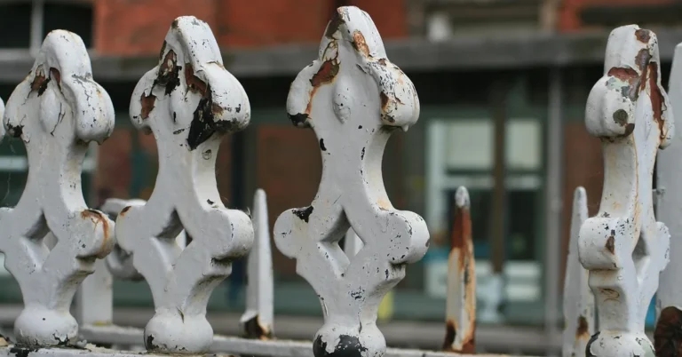 White-painted iron fence finials with chipped paint and rust