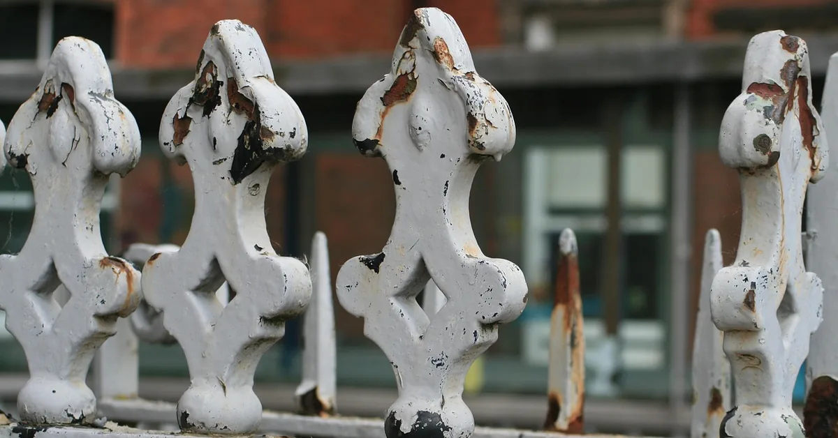 White-painted iron fence finials with chipped paint and rust