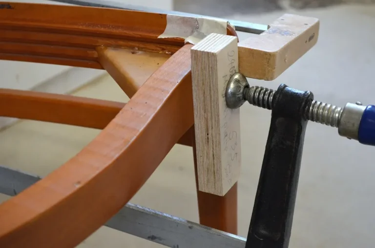 Bar clamp with a wooden caul block pressing on a glued wood joint