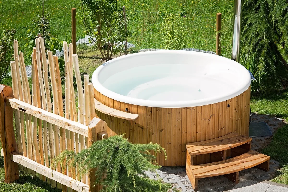 Round wood-clad soaking tub in a garden with wooden steps