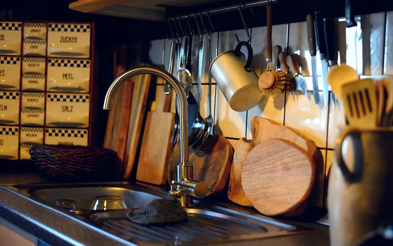 Wooden cutting boards propped upright by a kitchen sink to air dry evenly
