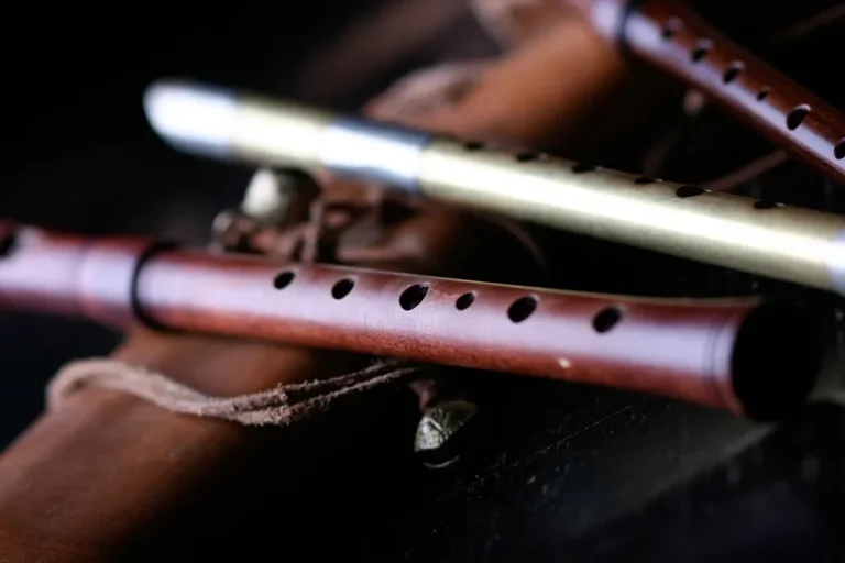Handmade wooden wind instruments with finger holes resting on a dark surface