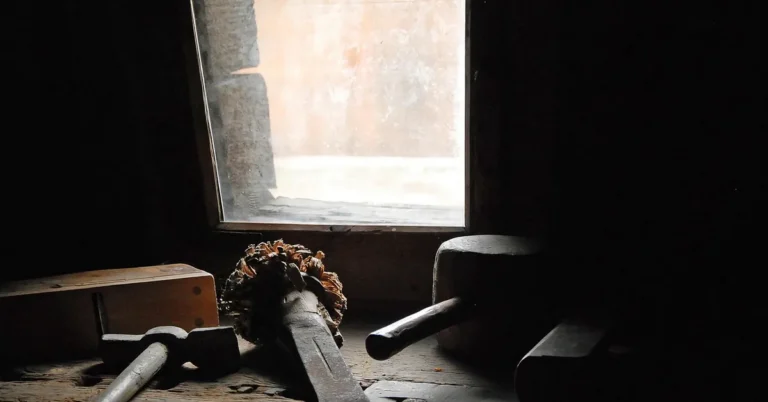 Traditional woodworking hand tools including chisels and mallet on a wood workbench