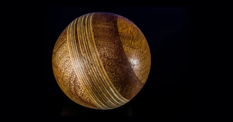 Turned hardwood ball with layered grain on a dark background