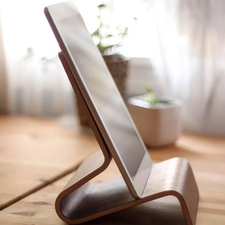 Wooden tablet stand holding a tablet upright on a pine desk