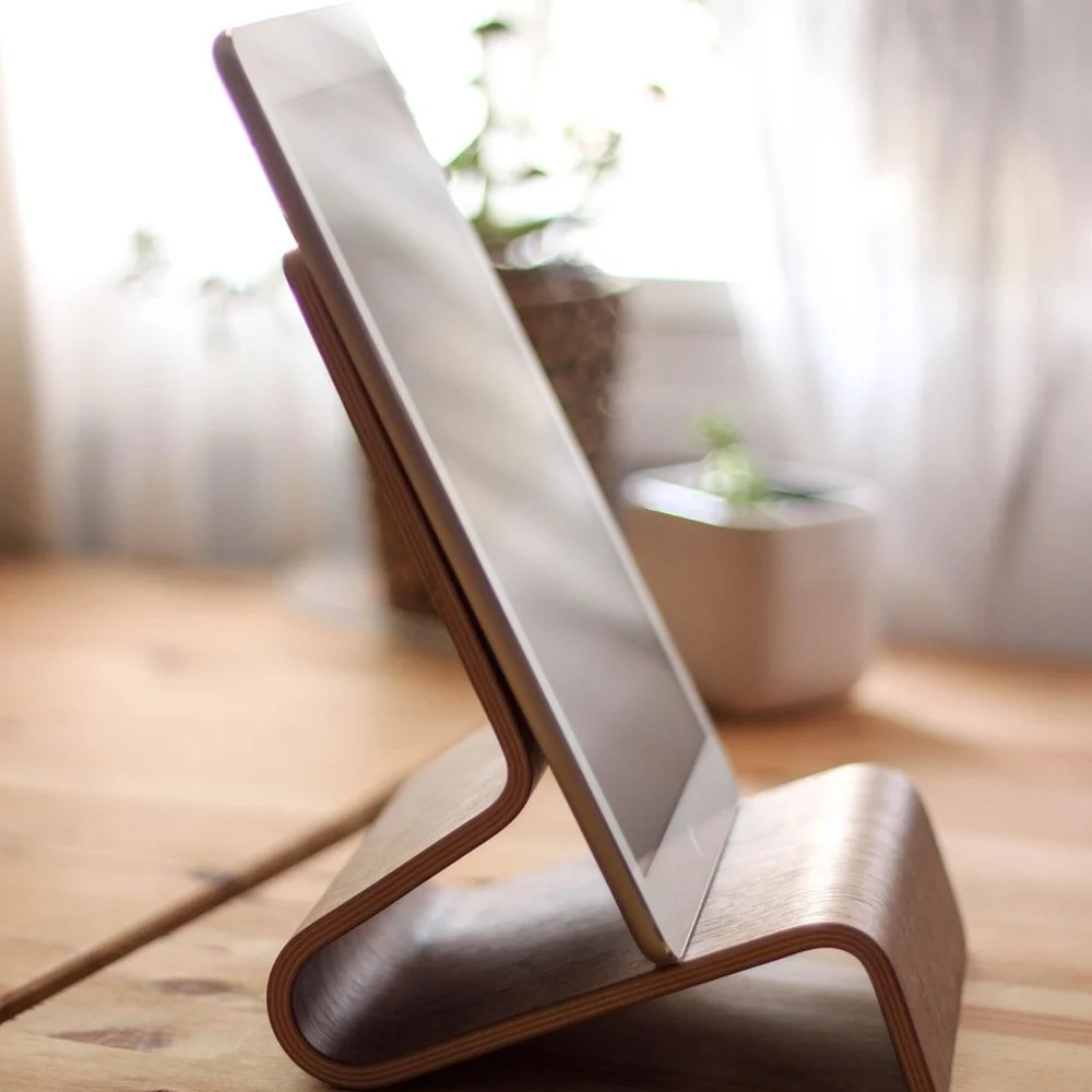 Wooden tablet stand holding a tablet upright on a pine desk