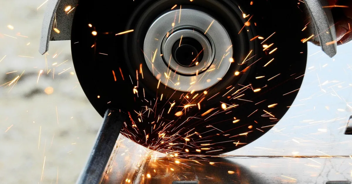 abrasive metal-cutting wheel slicing through a steel beam with sparks flying