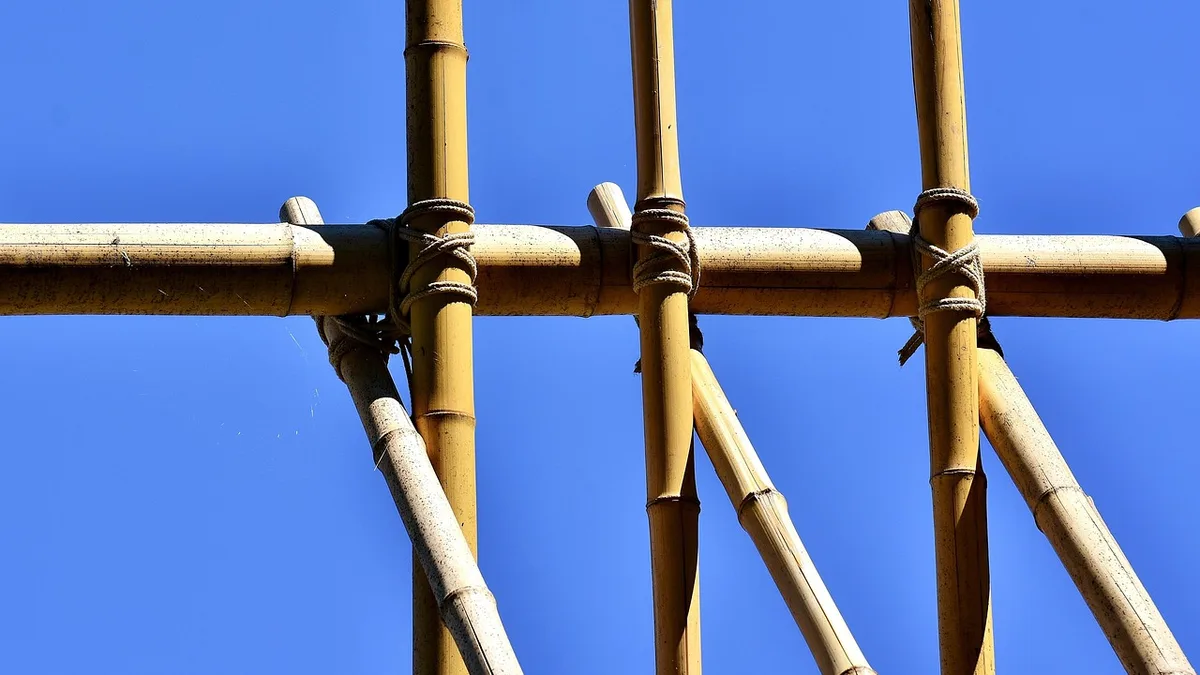 Bamboo poles lashed together into a frame against a blue sky