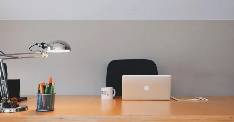 Light wood desk with laptop and coffee mug, the kind of daily wear a butcher block desk finish has to withstand
