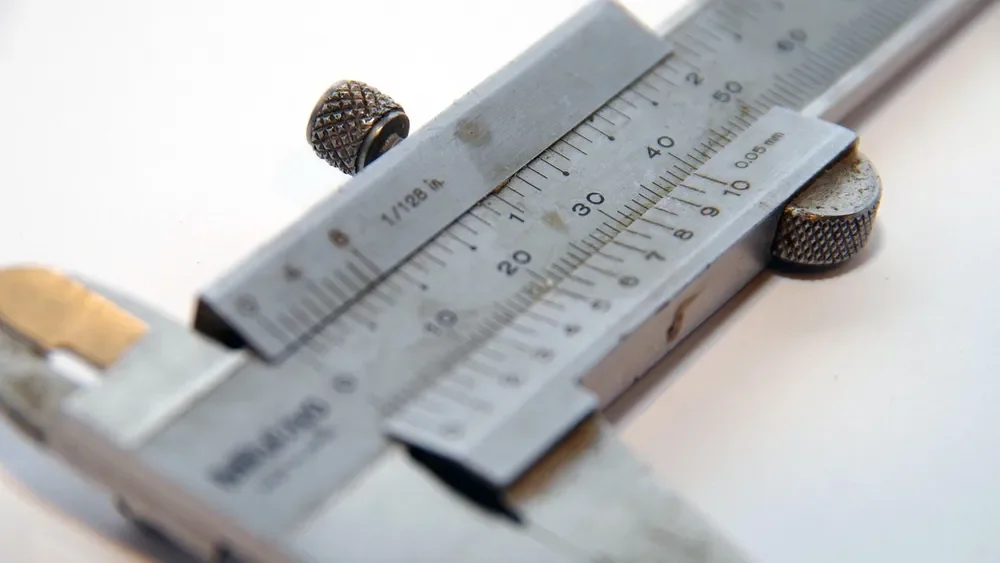 Close-up of a caliper scale used to read plywood thickness to the thousandth of an inch