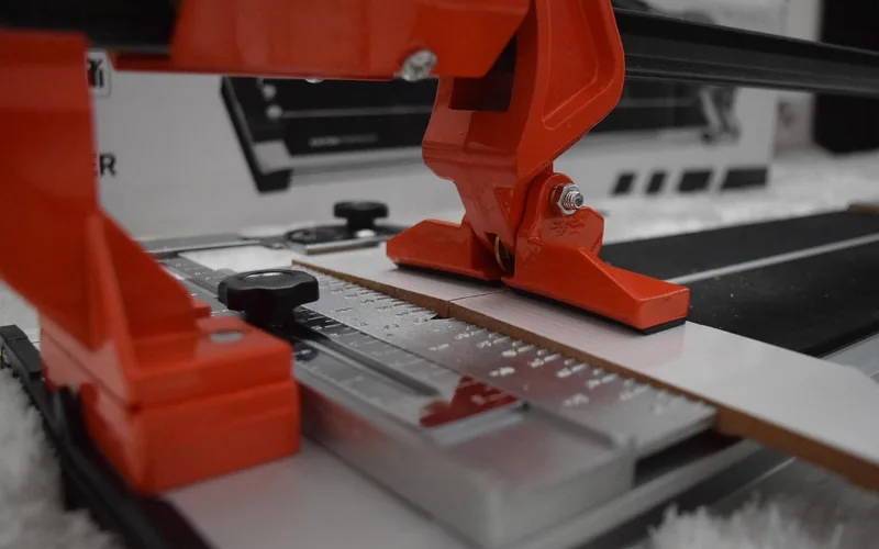 manual tile cutter scoring a ceramic tile before snapping it along the line