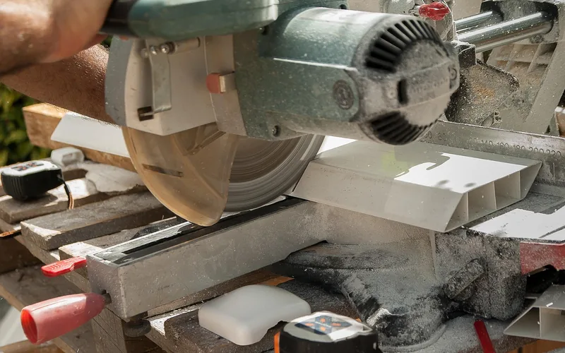 power saw fitted with a cutting blade slicing through trim material on a job site
