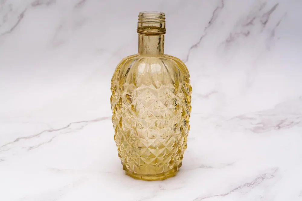 Textured amber glass bottle standing on a white marble surface