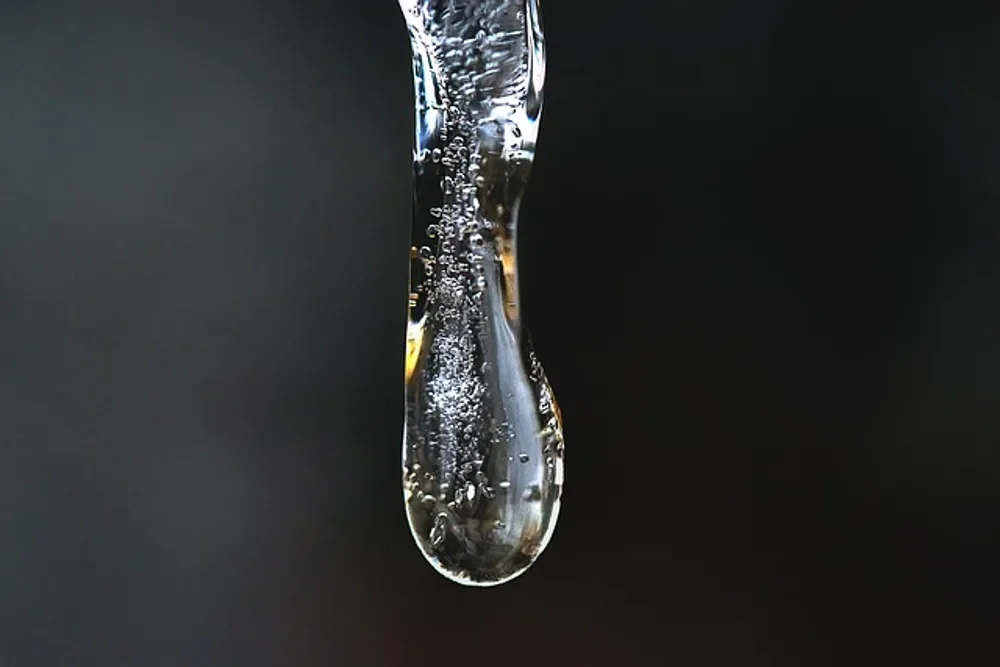Clear icicle with trapped air bubbles against a dark background