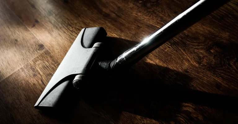 Cordless stick vacuum head cleaning a wood-look vinyl plank floor