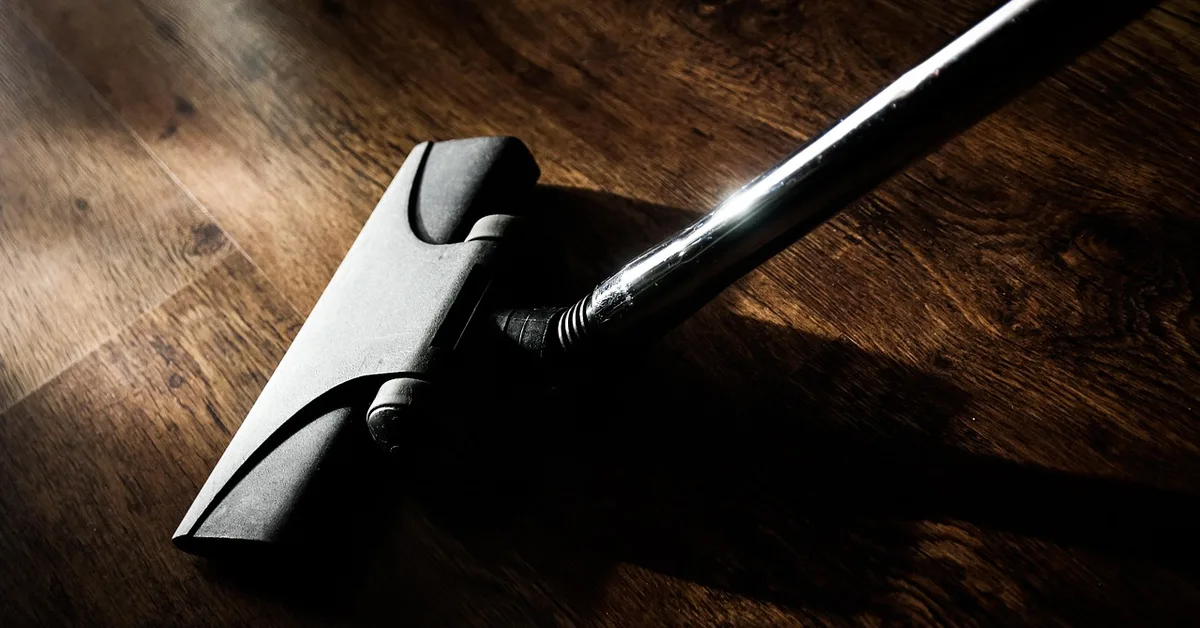 Cordless stick vacuum head cleaning a wood-look vinyl plank floor