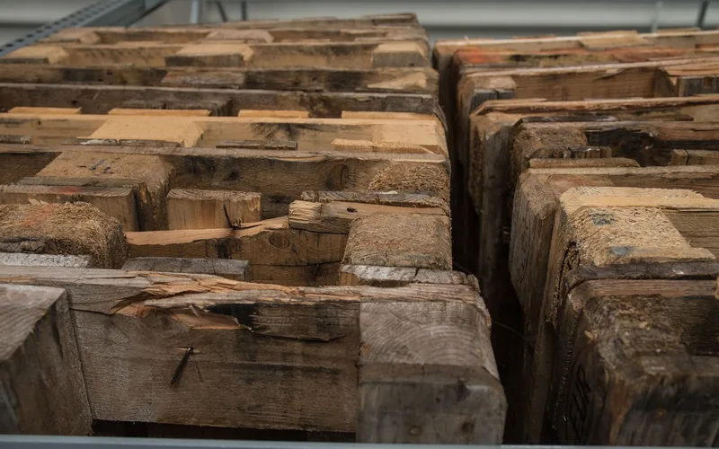 Cracked and worn used pallets stacked in a rack, typical of low-grade core pallets
