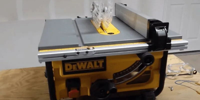 Dewalt table saw throat plate, riving knife, and safety glasses on the table before a cut