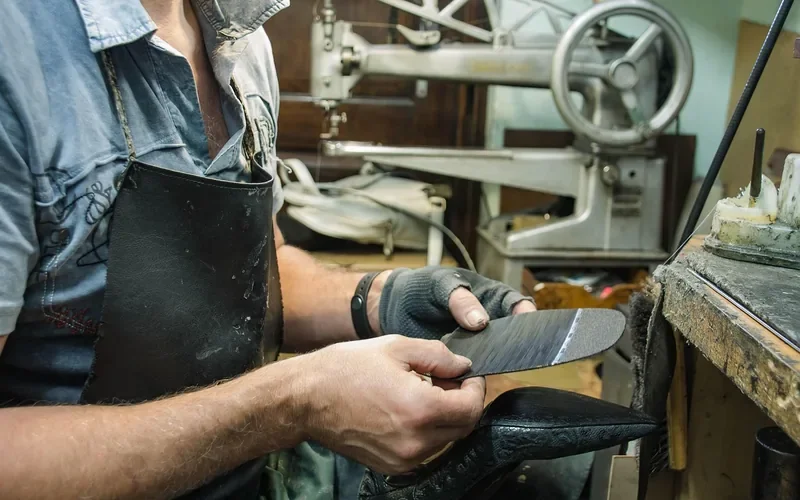 Cobbler holding a leather shoe and a new sole before bonding