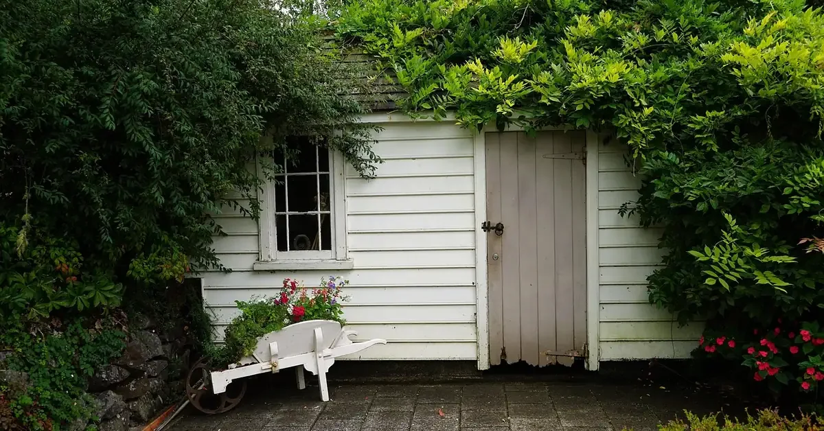 White wooden garden shed with a plank door, the kind of shed a lean-to can be added onto