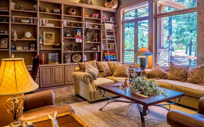 Living room with wooden shelving and furniture beside large sunlit windows