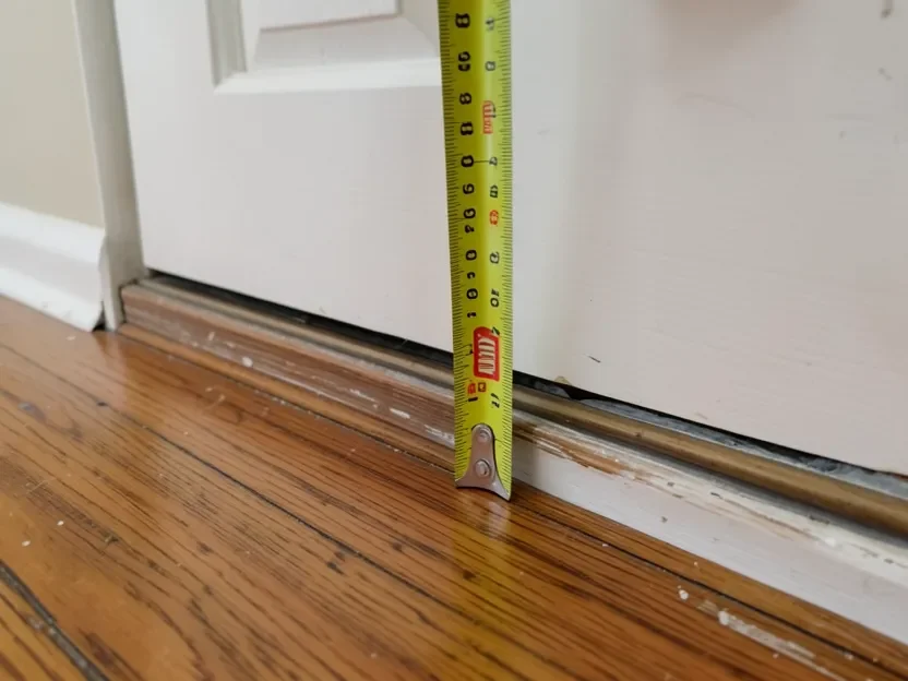 Measuring the height gap at a door threshold before tiling over an existing wood floor