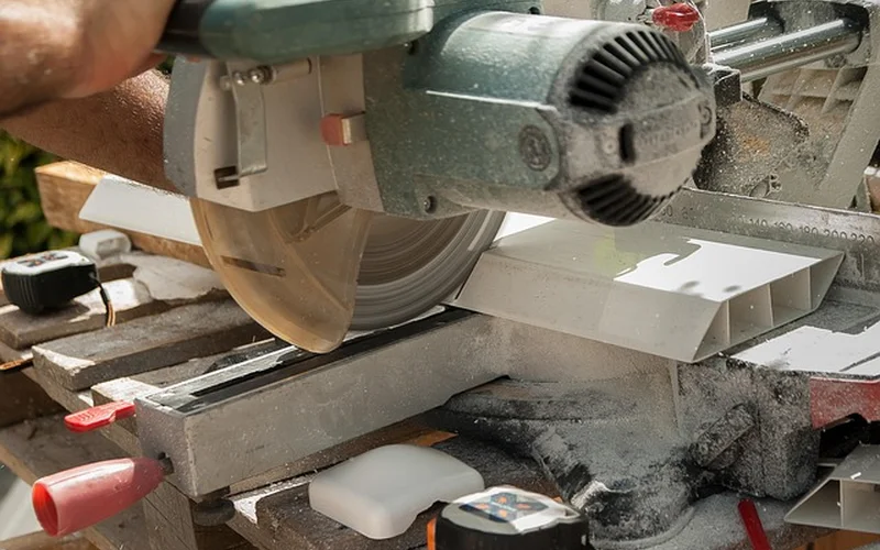 A miter saw in use in a home workshop, the same saw type used for angled aluminum cuts