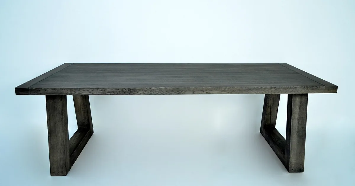 Solid oak dining table on two trestle legs inset from the tabletop ends