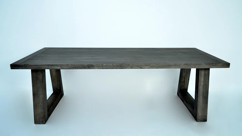 Rectangular oak table with a thick top on two U-shaped leg frames and no apron rails