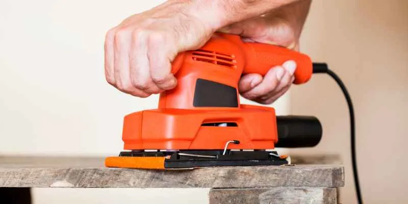 Orbital sander smoothing the edge of a wood board before finishing