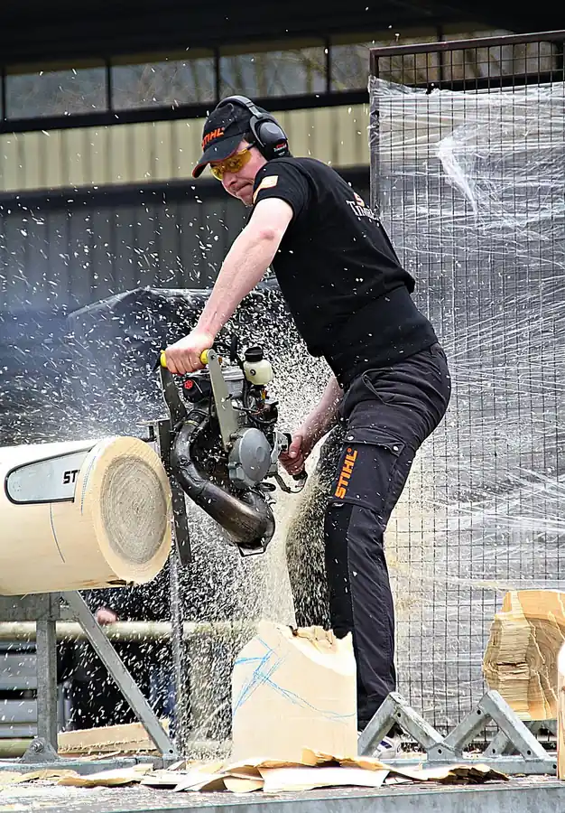 Operator using a two-handed grip on a rear-handle chainsaw at ground level Operator using a two-handed grip on a rear-handle chainsaw at ground level