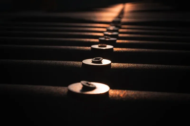 Row of screw heads with washers fastening a corrugated metal roof panel Row of screw heads with washers fastening a corrugated metal roof panel