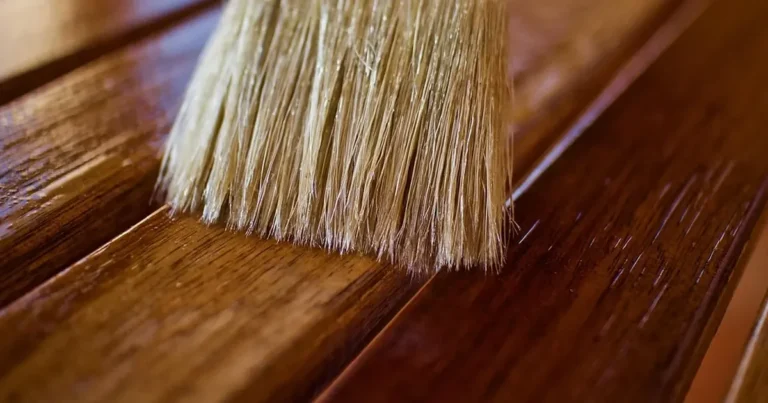 Natural-bristle brush applying stain to dark wood slats