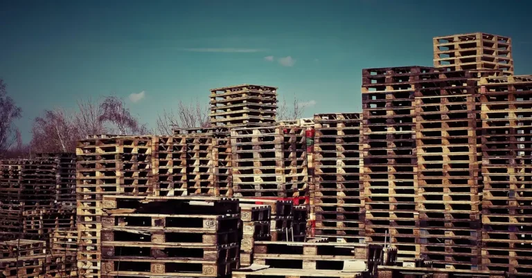 Tall stacks of used wooden pallets at an outdoor pallet yard