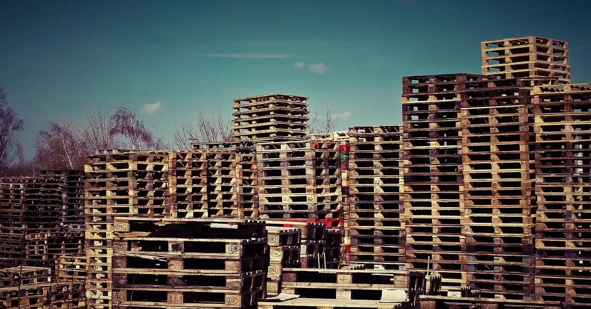 Tall stacks of used wooden pallets at an outdoor pallet yard