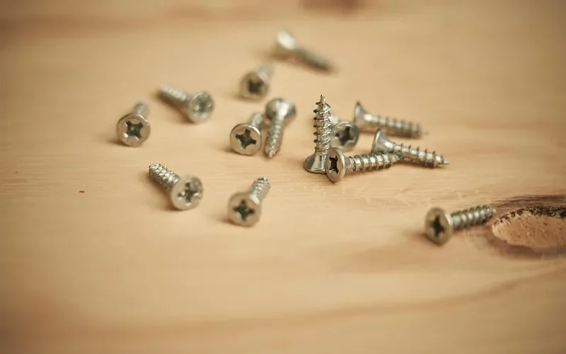 small wood screws scattered on a wooden plank small wood screws scattered on a wooden plank