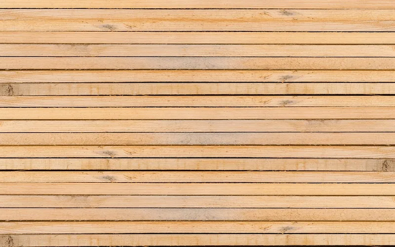 Stack of orange-toned lumber planks with visible knots ready for staining