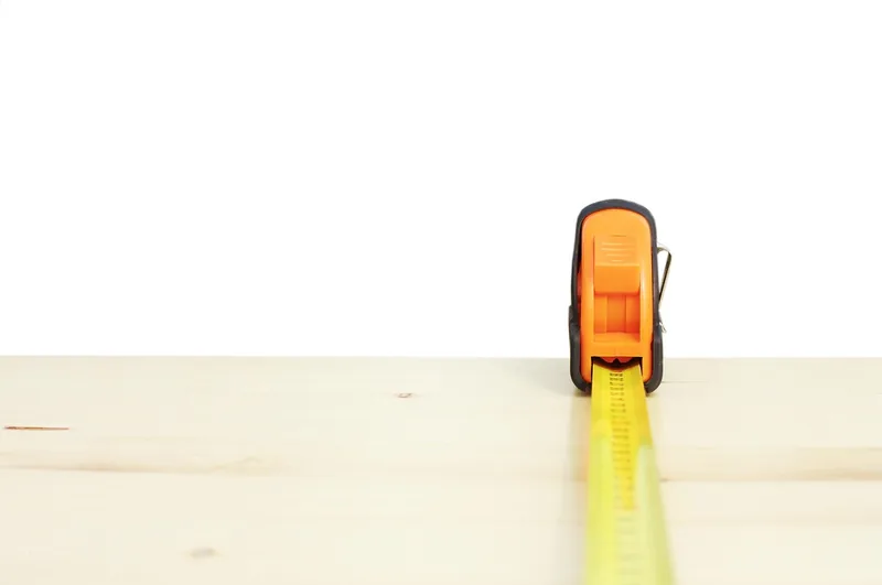 Tape measure extended along a pine board edge Tape measure extended along a pine board edge