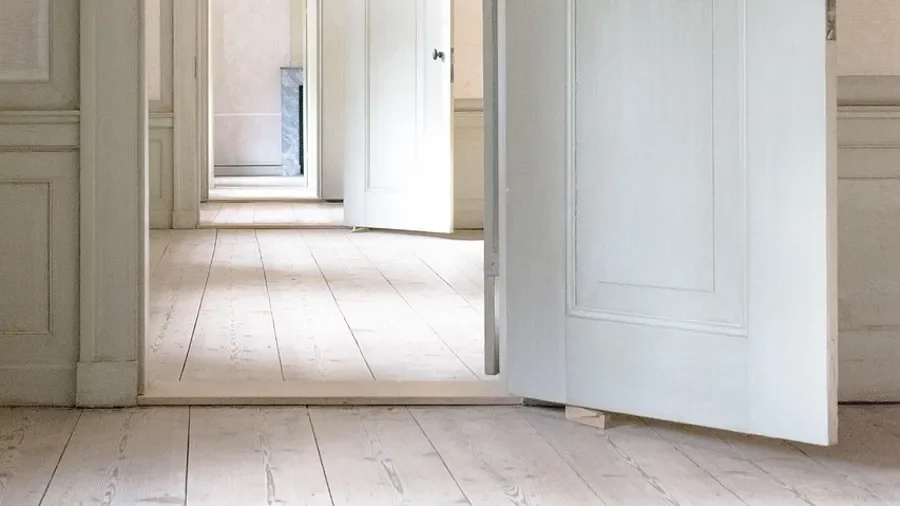 Wainscoting panels below a chair rail beside an open door, showing equal panel widths along the wall