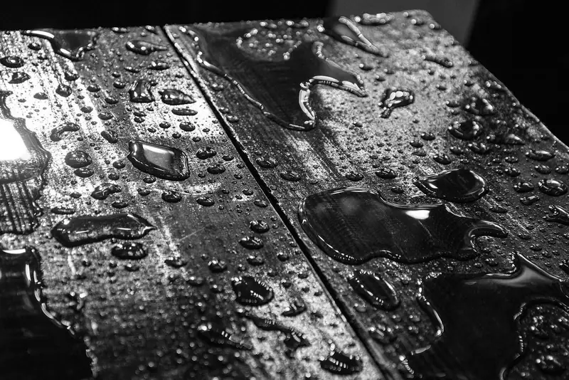 Water pooled on dark wood boards after a spill Water pooled on dark wood boards after a spill
