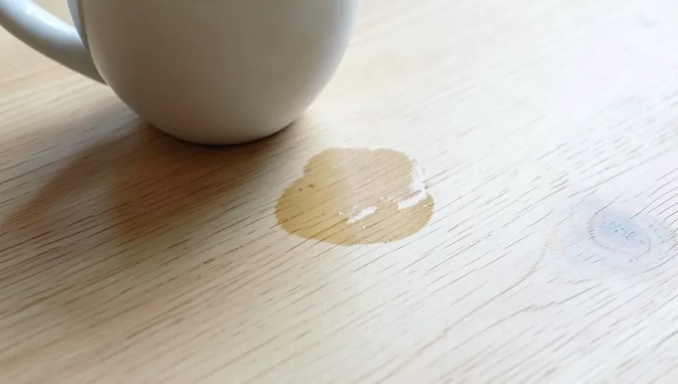 Visible water ring stain mark on a light colored wood tabletop near a coffee cup