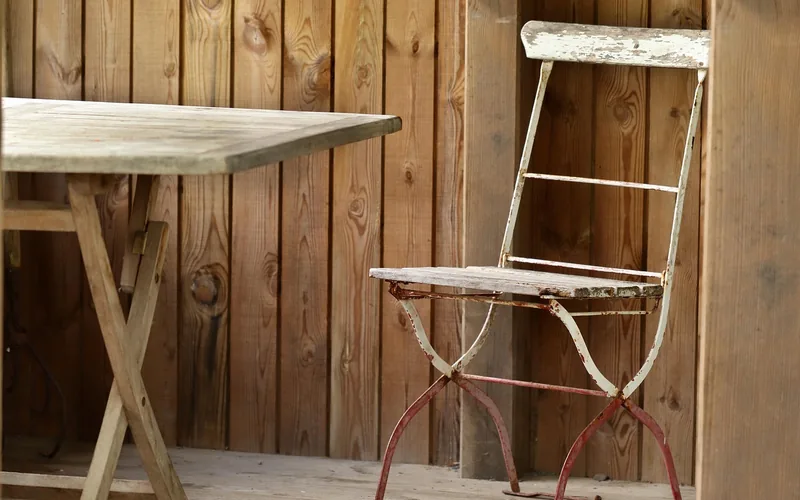 Weathered outdoor wood table showing natural graying and surface cracking from UV exposure Weathered outdoor wood table showing natural graying and surface cracking from UV exposure
