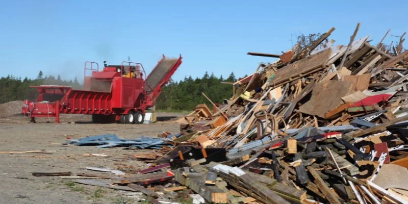 Industrial wood chipper processing scrap lumber at a recycling facility