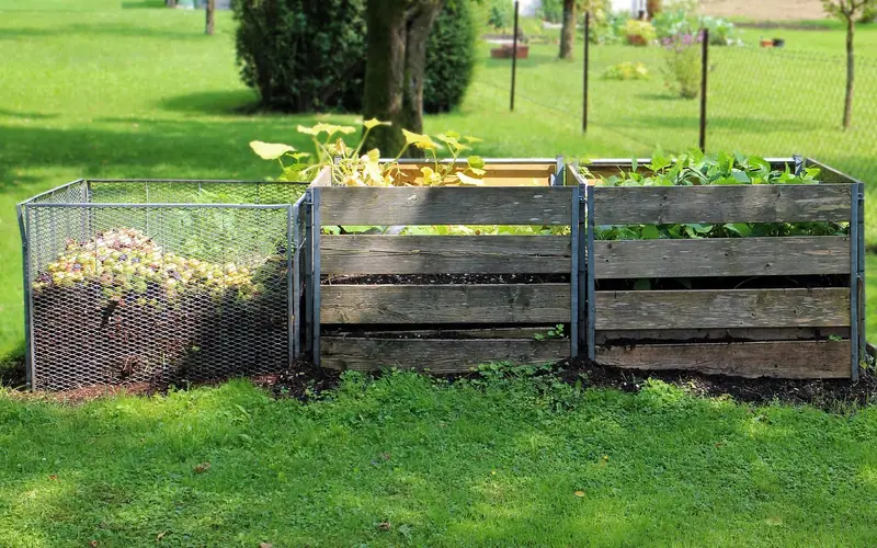 wooden compost bins in a garden where small amounts of wood ash can be mixed in wooden compost bins in a garden where small amounts of wood ash can be mixed in