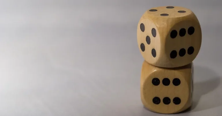 Two handmade-style wooden dice stacked on a grey surface