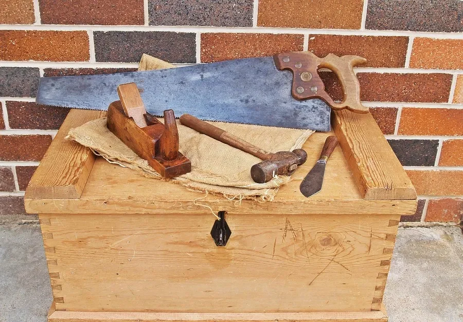 Pine tool chest with a hand saw, plane and hammer on the lid