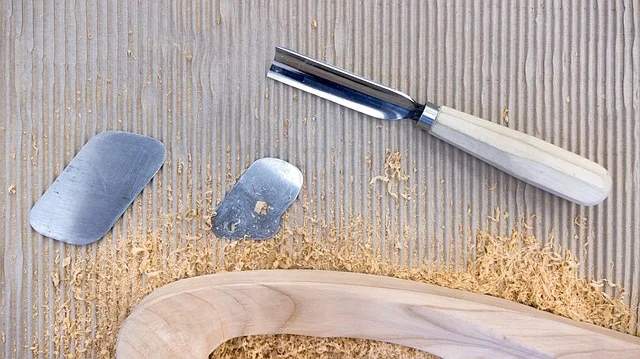 Wood carving gouges and chisels shaping a curved wooden piece with fresh shavings
