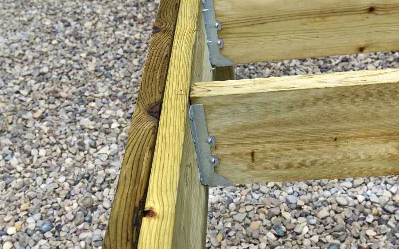 Close-up of a deck joist corner with galvanized joist hangers, ready for joist tape application
